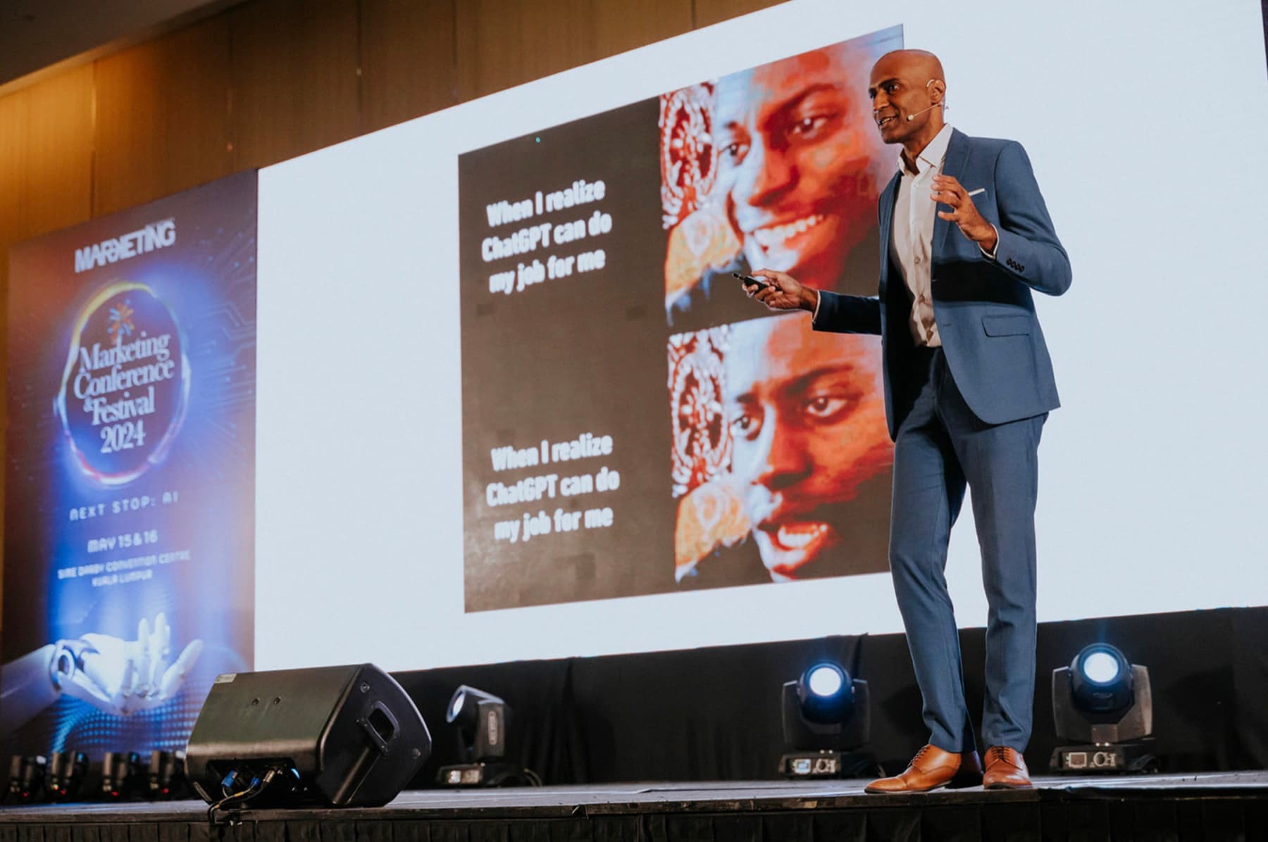 Indhran Seghar on a conference stage, a large screen behind him showing an article about AI and jobs